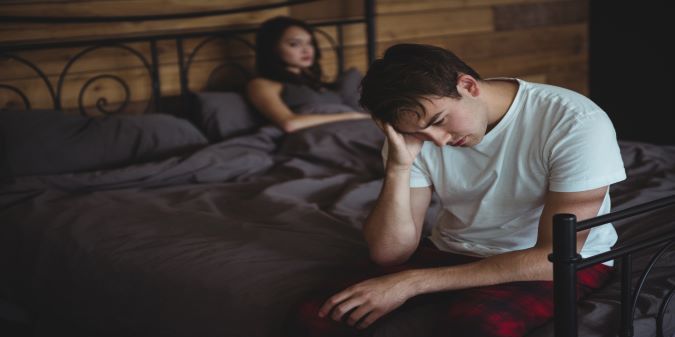 Upset couple ignoring each other on bed